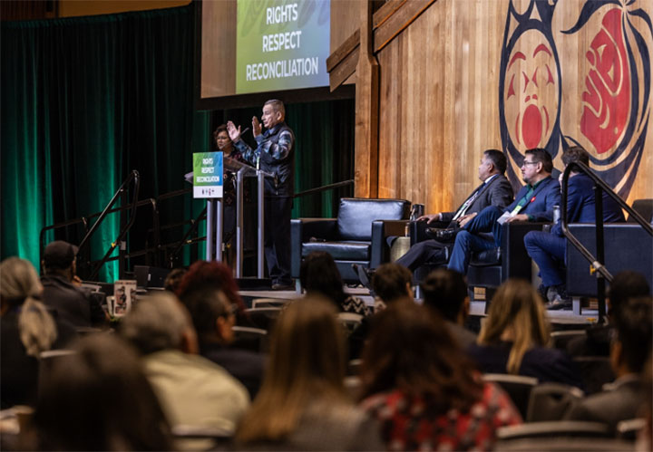 Panelists on stage giving a talk on rights, respect, and reconciliation